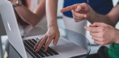 Close up of a laptop with fingers pointing at it